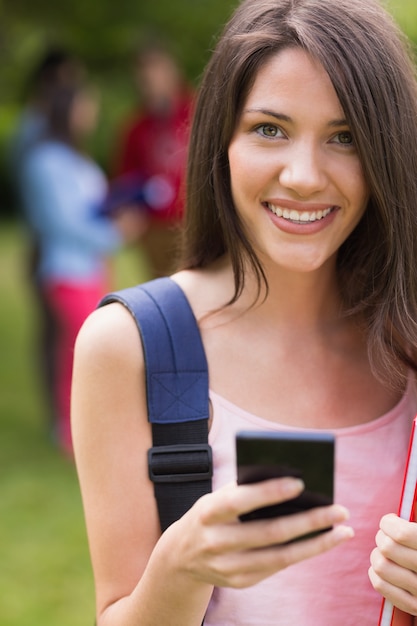 Pretty student sending a text outside on campus