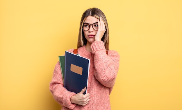 退屈な本とバックパックの後に欲求不満と眠い退屈を感じているかなりの学生女性