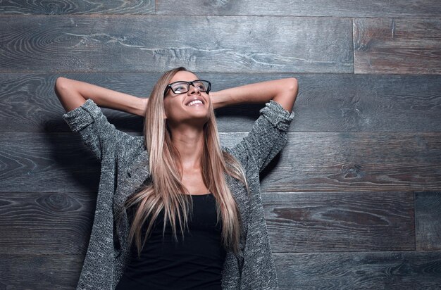 Pretty stylish girl standing near gray wall