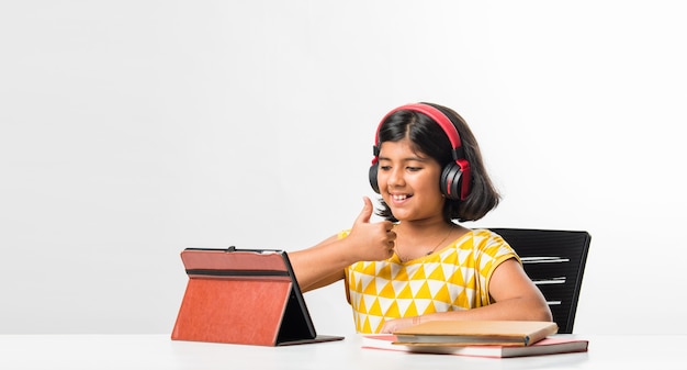 Pretty stylish Indian asian schoolgirl studying attending online lesson at home