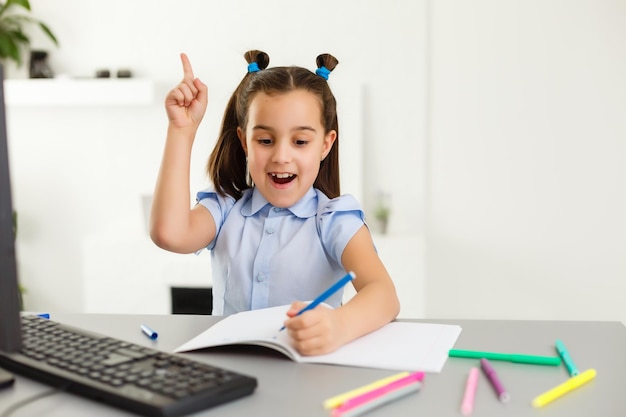 Pretty stylish schoolgirl studying homework math during her online lesson at home, social distance during quarantine, self-isolation, online education concept, home schooler