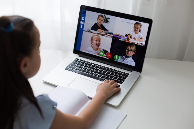 Pretty stylish schoolgirl studying homework math during her online lesson at home, social distance during quarantine, self-isolation, online education concept, home schooler