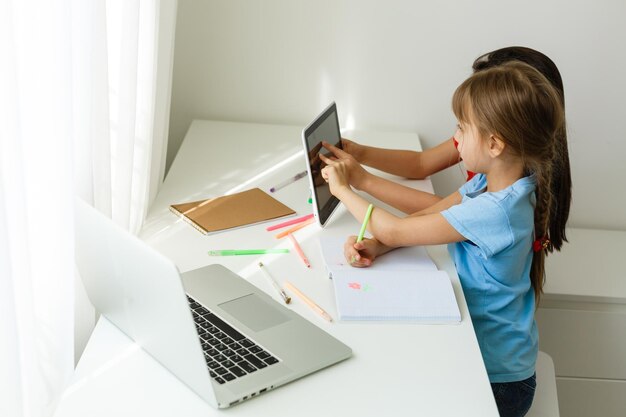 Pretty stylish schoolgirls studying during her online lesson at home, social distance during quarantine, self-isolation, online education concept