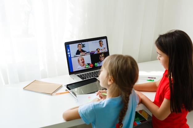 Pretty stylish schoolgirls studying during her online lesson at home, social distance during quarantine, self-isolation, online education concept