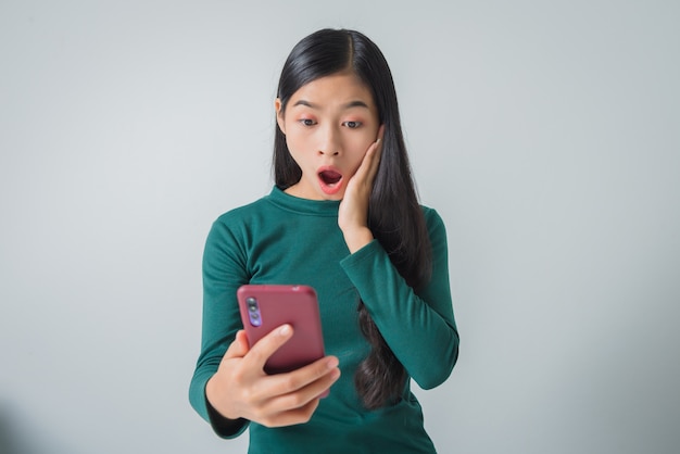 Pretty surprised young woman holds smartphone