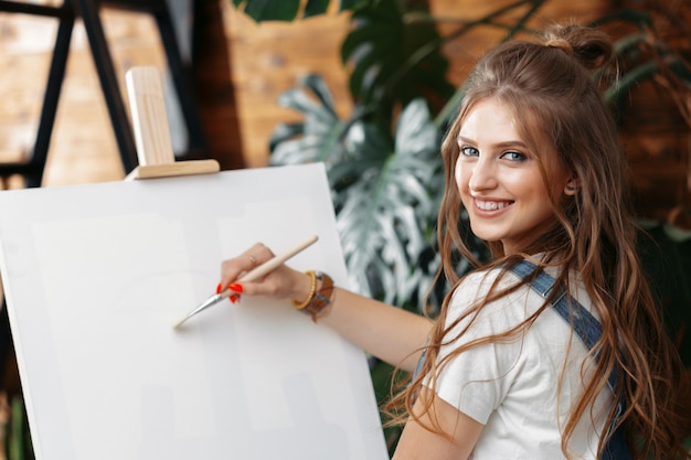 Pretty talented female painter painting on easel