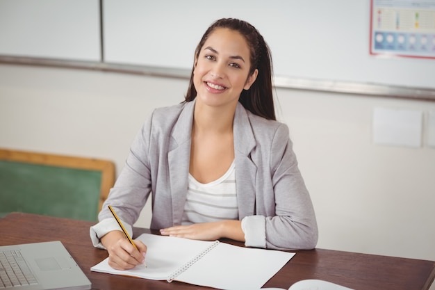 pretty teacher correcting at her desk in a classroom