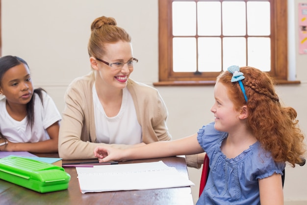 Photo pretty teacher helping pupil in classroom