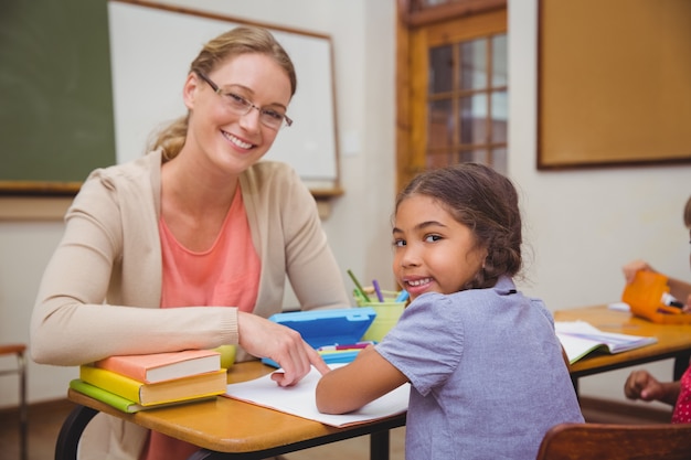 Photo pretty teacher helping pupil in classroom