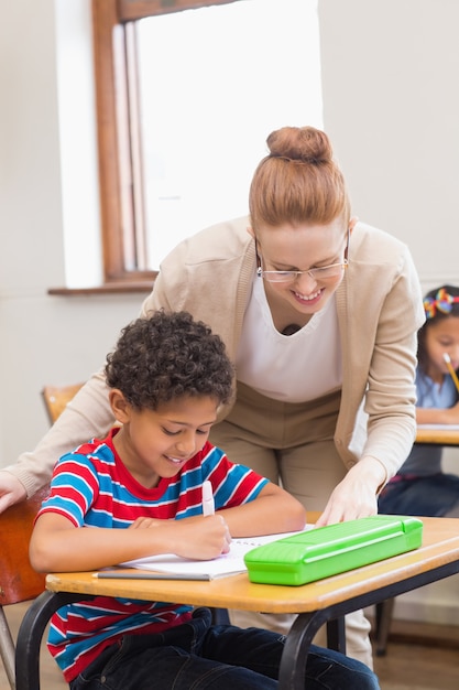 Pretty teacher helping pupil in classroom 