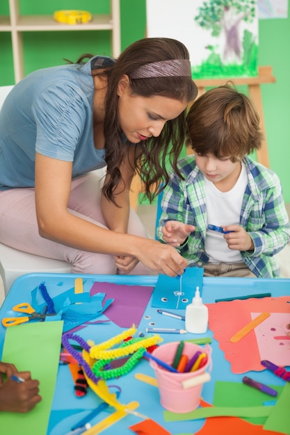 Pretty teacher helping pupil in classroom 