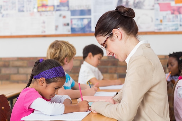 Pretty teacher helping pupil in classroom