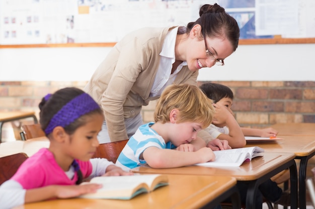 Pretty teacher helping pupil in classroom