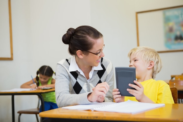 Pretty teacher helping pupil in classroom