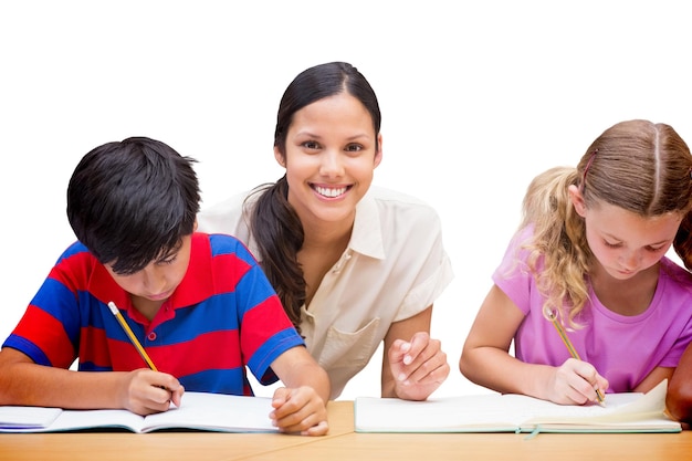 Pretty teacher helping pupils in library against white background with vignette