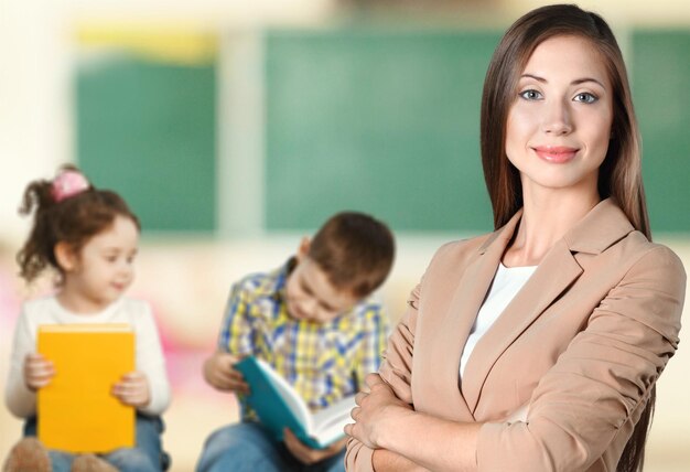 Pretty teacher smiling at camera at back of classroom at the elementary school