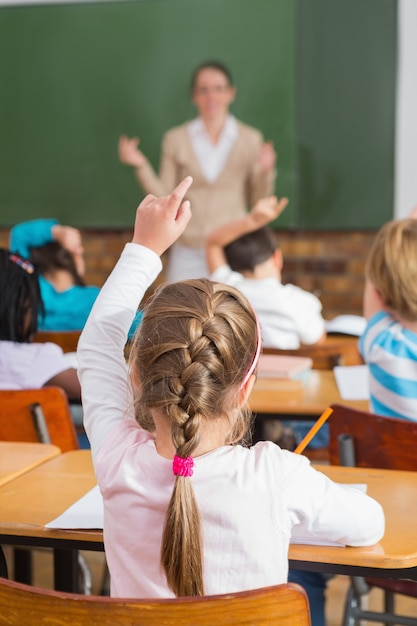 Pretty teacher talking to the young pupils in classroom