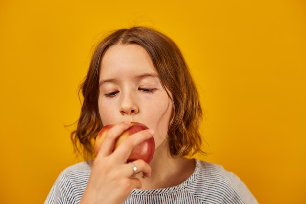 きれいな 10 代の女の子の子供が新鮮な赤いリンゴをかむ食べる