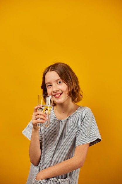 Pretty teen girl child with a fresh glass of water isolated