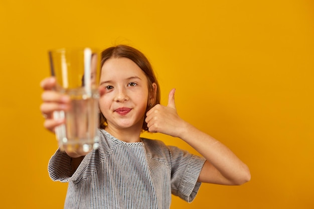 Pretty teen girl child with a fresh glass of water isolated