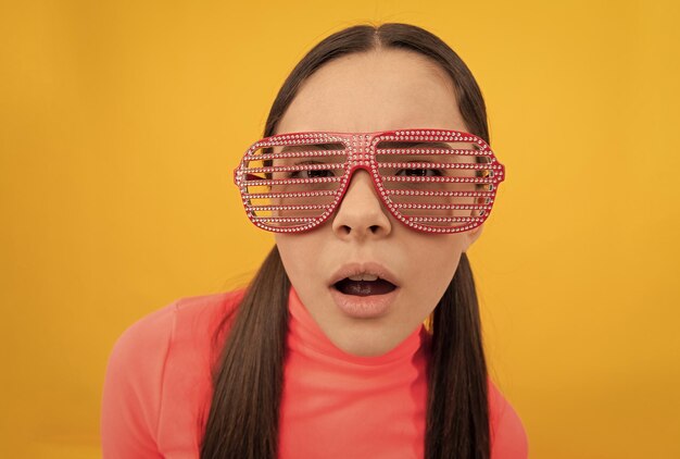 Pretty teen girl making selfie in glamour party eyeglasses on yellow background selfie