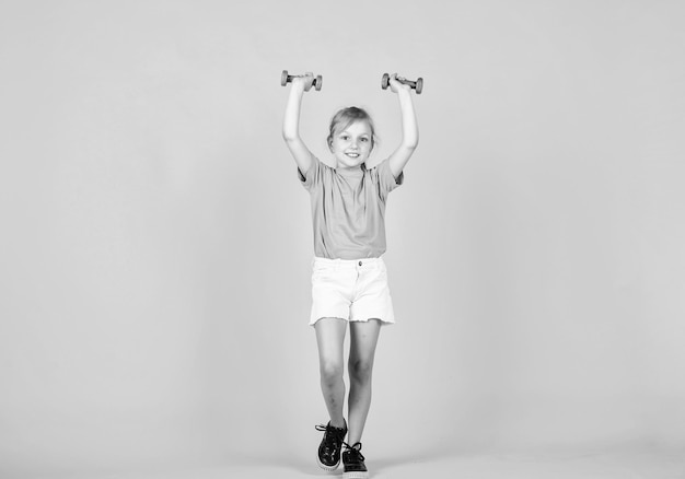 Pretty teen girl with barbells tools for training sport