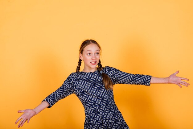 Pretty teenager girl smiling on camera looking cheerful on yellow background. Positive emotions