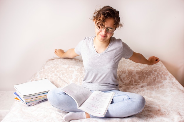 Pretty teenager girl stretches on the bed during home schooling