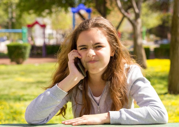 夏の公園で携帯携帯電話のスマートフォンを持つかなり10代の女の子