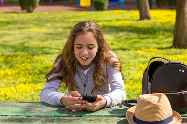 Photo pretty teenager girl with mobile cellphone smartphone at the summer park