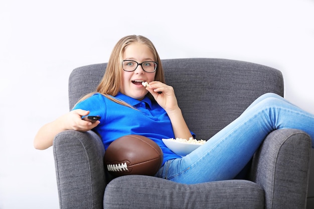 Pretty teenager watching rugby on TV at home