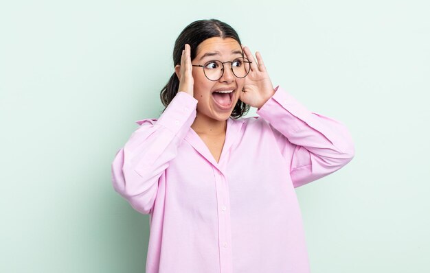 Pretty teenager woman feeling happy, excited and surprised, looking to the side with both hands on face