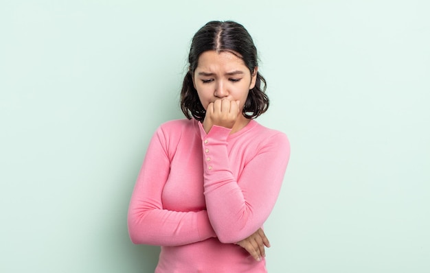 Pretty teenager woman feeling serious, thoughtful and concerned, staring sideways with hand pressed against chin