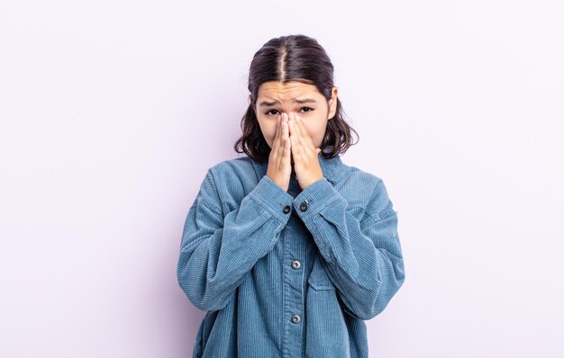 Pretty teenager woman feeling worried, hopeful and religious, praying faithfully with palms pressed, begging forgiveness