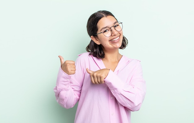 Pretty teenager woman smiling cheerfully and casually pointing to copy space on the side, feeling happy and satisfied