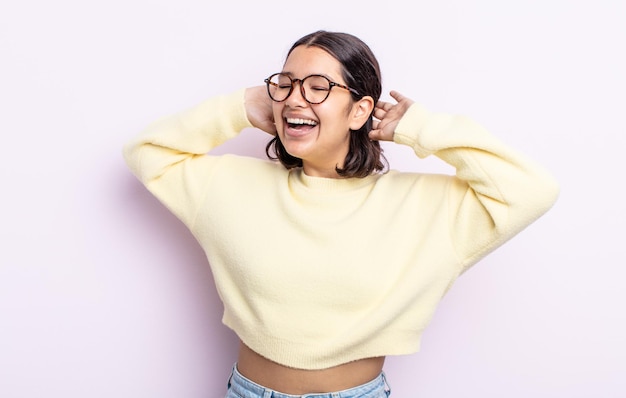 Pretty teenager woman smiling and feeling relaxed, satisfied and carefree, laughing positively and chilling