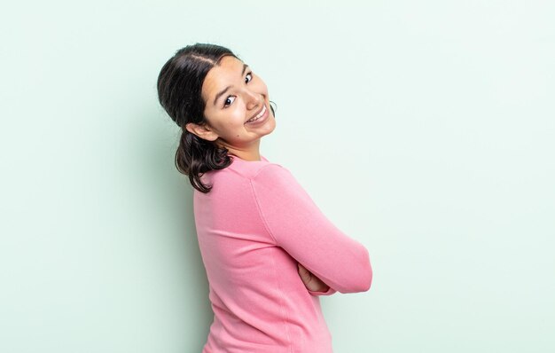 Pretty teenager woman smiling gleefully, feeling happy, satisfied and relaxed, with crossed arms and looking to the side
