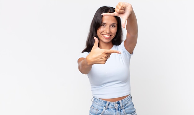 Pretty thin hispanic woman feeling happy, friendly and positive, smiling and making a portrait