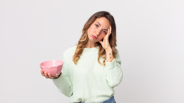 Pretty thin woman feeling bored, frustrated and sleepy after a tiresome and holding an empty pot bowl