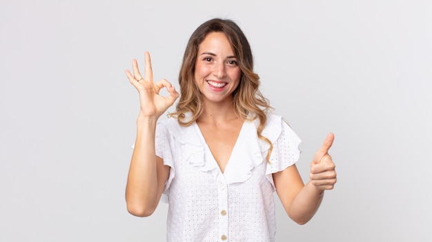 Pretty thin woman feeling happy, amazed, satisfied and surprised, showing okay and thumbs up gestures, smiling