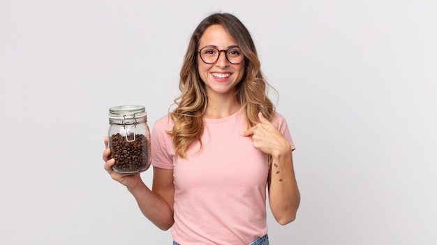 Pretty thin woman feeling happy and pointing to self with an excited and holding a coffee beans bottle