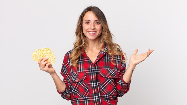 Pretty thin woman feeling happy surprised realizing a solution or idea and holding a diet rice cakes