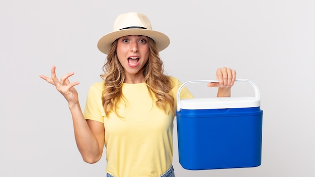 Pretty thin woman feeling happy, surprised realizing a solution or idea and holding a  summer picnic fridge