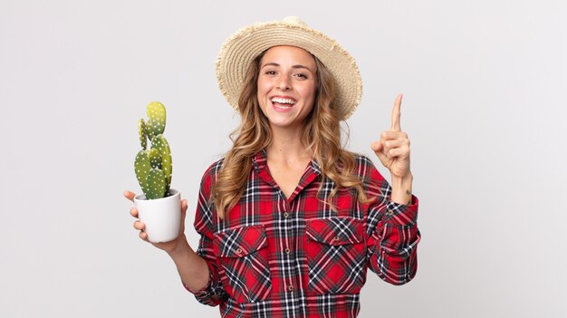 Foto donna piuttosto magra che si sente un genio felice ed eccitato dopo aver realizzato un'idea con in mano un cactus. concetto di contadino