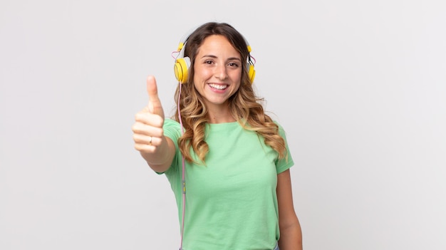 Pretty thin woman feeling proud,smiling positively with thumbs up listening music with headphones