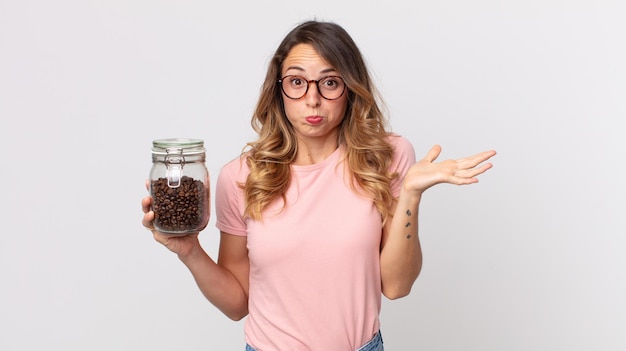 Pretty thin woman feeling puzzled and confused and doubting and holding a coffee beans bottle