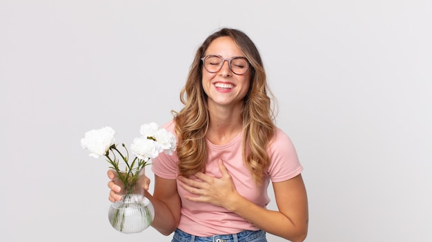 Pretty thin woman laughing out loud at some hilarious joke and holding decorative flowers