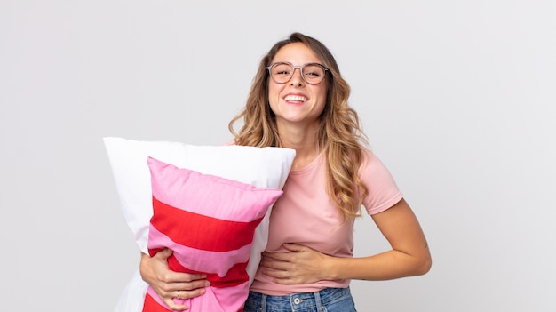pretty thin woman laughing out loud at some hilarious joke wearing pajamas and holding a pillow