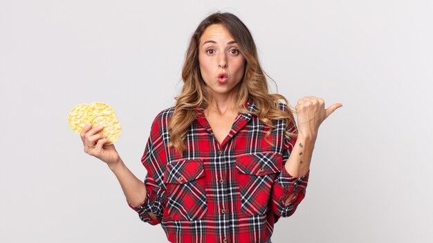 pretty thin woman looking astonished in disbelief and holding a diet rice cakes