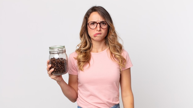 Pretty thin woman looking puzzled and confused and holding a coffee beans bottle